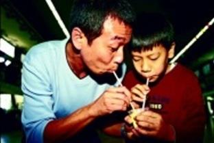 教職員親子趣味競賽，總務處秘書林錦河公子林祖捷和營繕組王清一合力吃布丁。