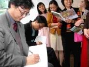 參與漫畫展開幕典禮的漫畫家們，受到本校師生的熱倩包圍，忙著在本次漫畫展發行的專冊上簽名留念。（記者陳震霆攝）