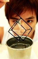 物理二陳思宇在物理展中玩趣味物理實驗，鋼模型沾上肥皂水後，骨架間形成晶瑩剔透的多面體。物理系碩二江定遠解釋說，根據表面張力原理，肥皂水會形成總表面積最小、所需能量最小的結構。（記者陳振堂攝）