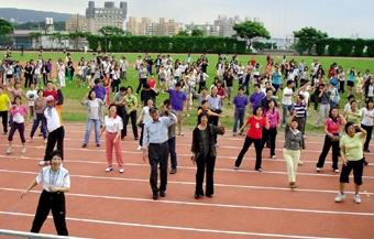 18日本校舉行日行萬步健行活動，體育名人紀政與楊傳廣蒞校，與校長張家宜及師生三百餘人在操場熱身，準備出發。（圖/記者  嘉翔）