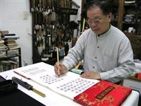 文錙藝術中心副主任張炳煌端坐並帶著戒慎緊張的心情，以羊毫正楷書寫正副總統當選證書。