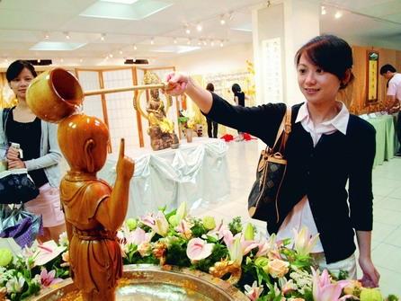 正智佛學社上週在商管展示廳舉辦浴佛祈福活動，上圖女學生正在浴佛，洗滌佛像身上的塵垢。（攝影�劉瀚之）