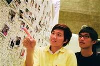 攝影成果展「我愛攝影」的這面拍立得照片牆十分熱門，引起許多同學拍照留念，競相討論照片中的人。（攝影�林奕宏）