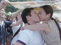 東南亞所翁履中同學在烈日下抱著女友親吻一個小時，挑戰一萬元獎金，親友團在一旁加油打氣，還用報紙幫忙遮陽。（攝影�昂力）
